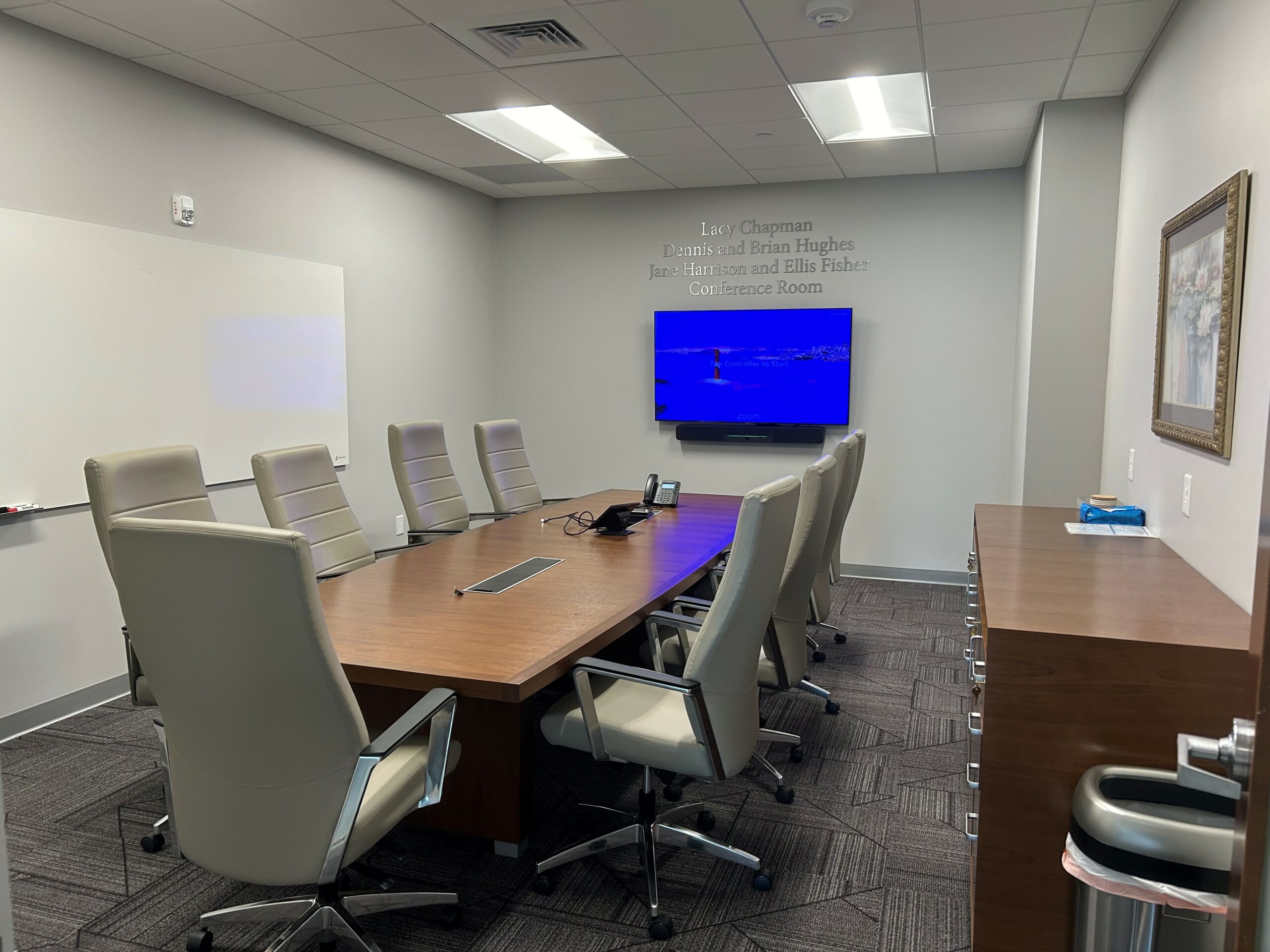 Conference room with table and chairs, white board and one wall mounted monitor