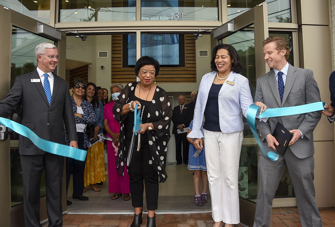 a group of people cutting a ribbon in front of a building