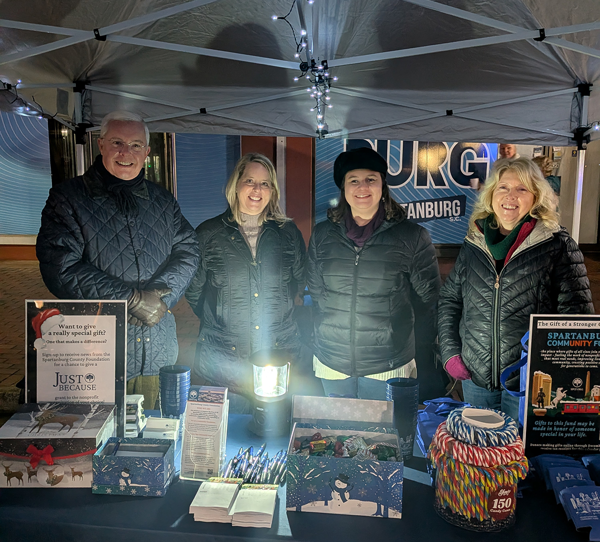 A photo of our individuals under a tent at an outdoor evening event.