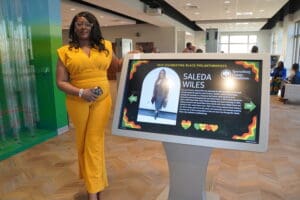 a woman standing next to a screen displaying an image