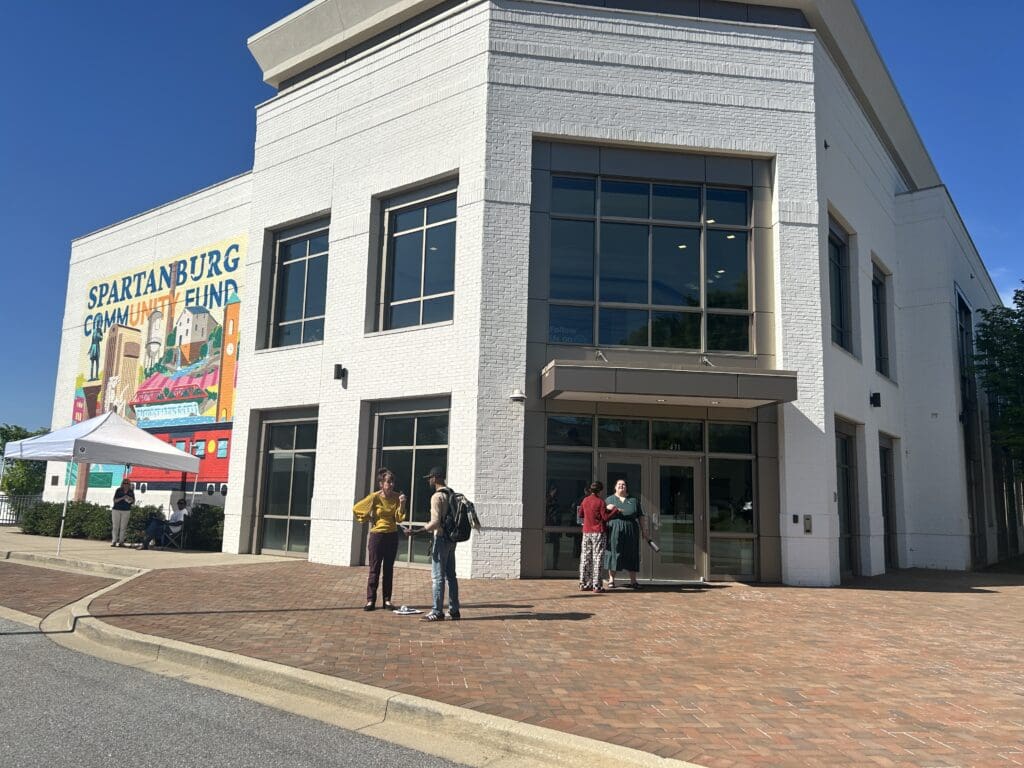 people standing in front of a building with a mural on one wall