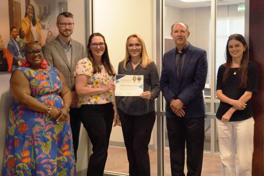 Six people standing together with one holding a certificate