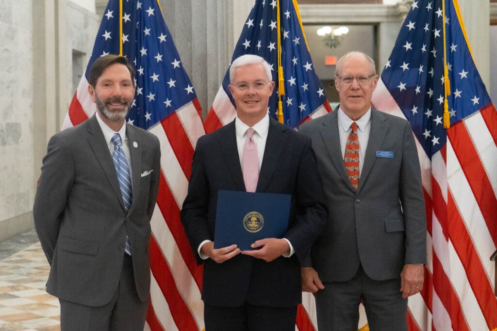 three men standing in front of American flags